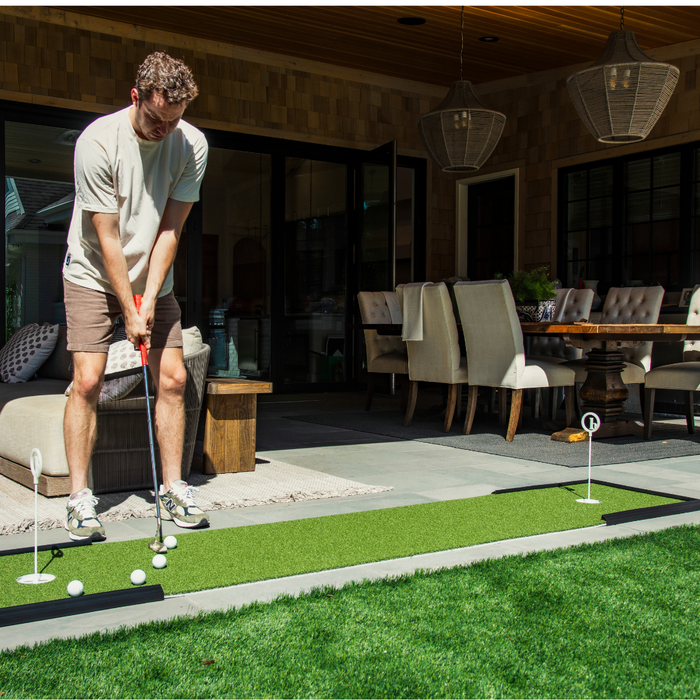 person practicing on a putting mat in their backyard