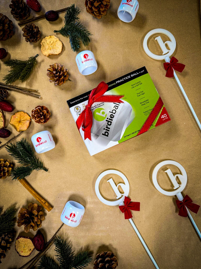 BirdieBall golf practice balls in festive holiday gift packaging with red ribbons, pinecones, and Christmas decorations.