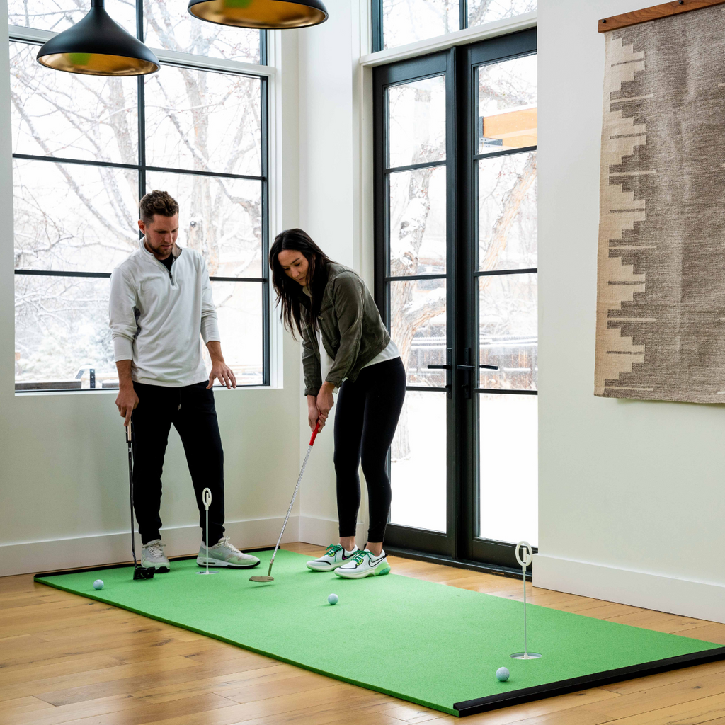 wide view of two people practicing their putting together on the best putting green