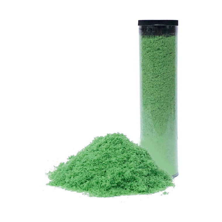 A clear plastic cylinder of BirdieBall Fill Material for Damaged RollTech Foam Putting Green stands upright beside a pile of the green powder on a white background, perfect for golf green repair and maintenance.