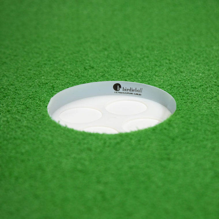 A close-up of the BirdieBall Putting Green Cup (Standard 1/2" deep) set in artificial turf—an essential accessory for your putting green.